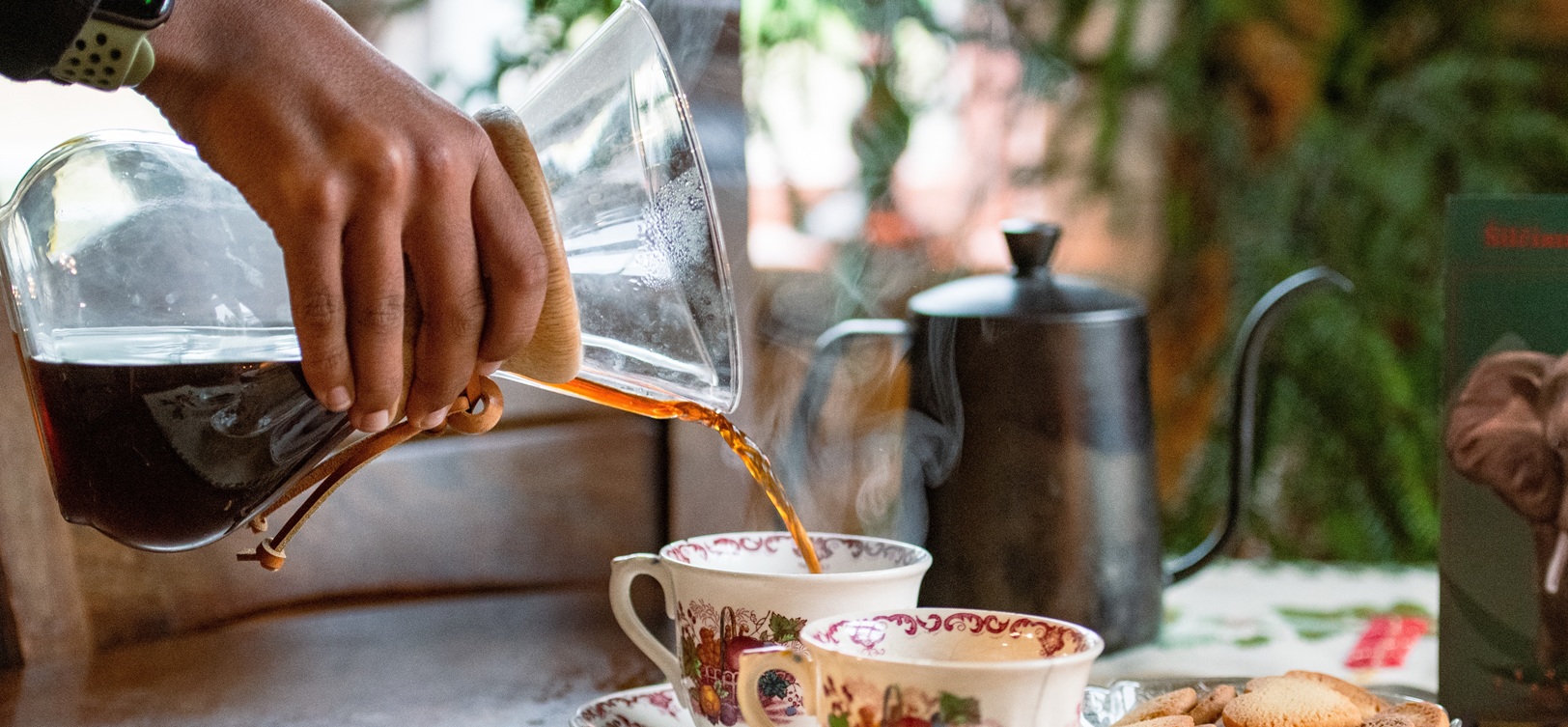 Filterkaffee wird aus einer Glaskaraffe in Tassen eingeschenkt