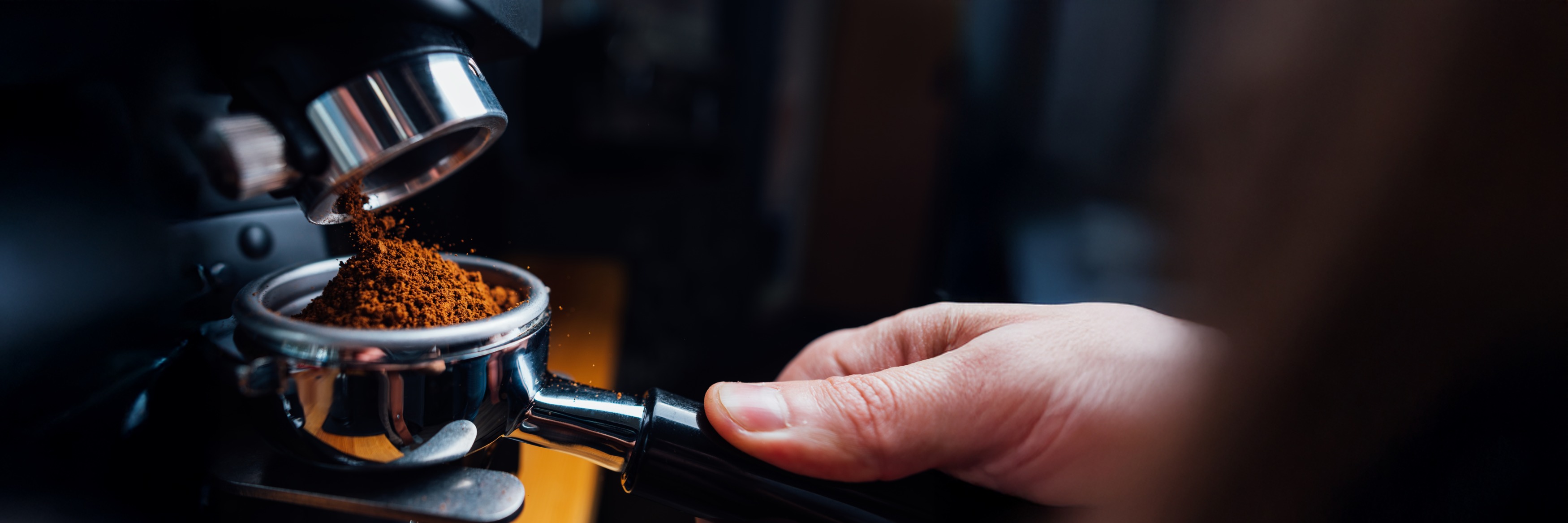 Gemahlener Kaffee fällt aus einer Mühle in einen Siebträger